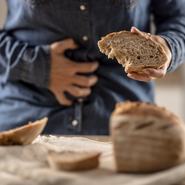 Woman can't eat bread and grain products because of gluten intolerance. A young celiac woman suffers from abdominal pain after eating fresh bread.