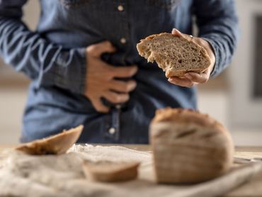 Woman can't eat bread and grain products because of gluten intolerance. A young celiac woman suffers from abdominal pain after eating fresh bread.