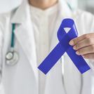 Orvos tart egy kék szalagot a vastagbélrák megelőzése jelképeként